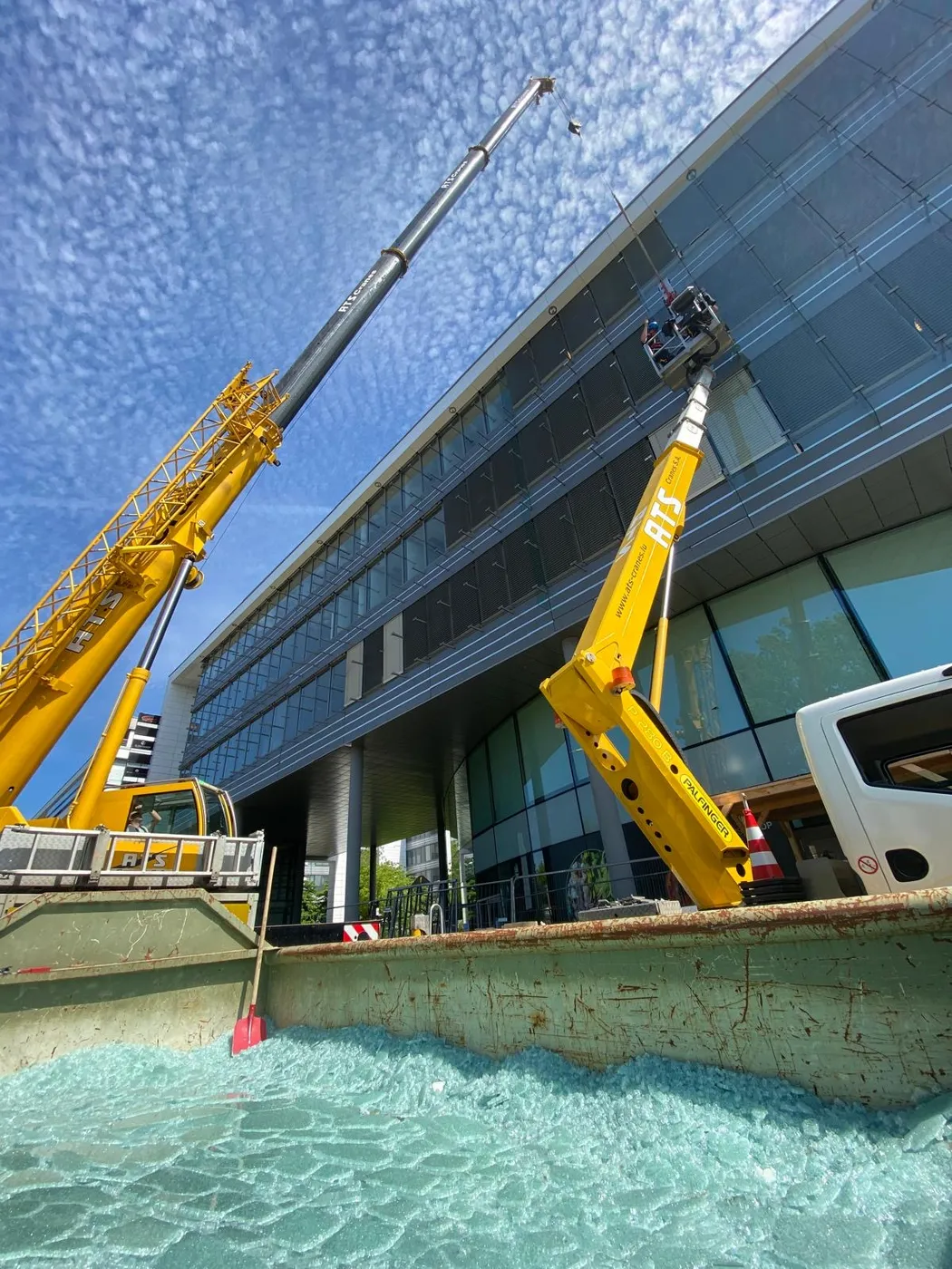 Remplacement de vitrages de façade à la grue au-dessus d'une benne de verre brisé — chantier Vitralux Bradtke Luxembourg